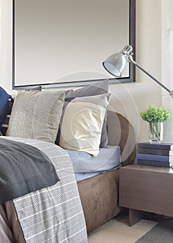 Modern bedroom with gray pillow and lamp on wooden bedside table