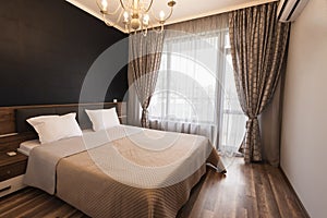 Modern bedroom interior design. Luxury bed room with brown color tone. Windows with long curtains and sheers