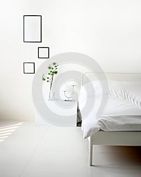 Modern bedroom with white bed, lamp and green ornamental and picture frame for mockup on wall with copy space.