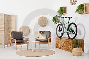 Modern bicycle and comfortable armchairs in living room interior