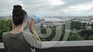 Modern big city skyline. Back view of a young beautiful girl enjoying the view. The girl undoing her long hair, turning