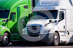 Modern big rigs long haul semi trucks stand in row on truck stop