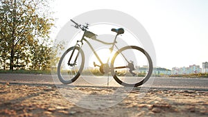 Modern black bicycle on an asphalt country road in summer against the backdrop of the sun. The concept of cycling and