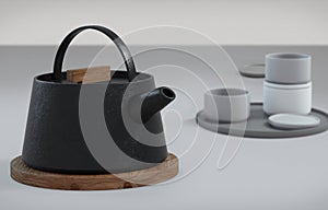 Modern black cast iron teapot and tea cups and a minimalist table white. side view, set for tea time. 3d rendering
