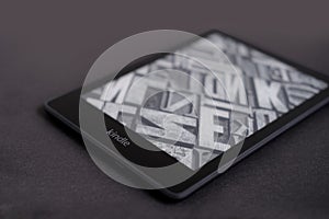 Modern black e-book reader, digital book Kindle, tablet computer device for displaying text electronically on black background,