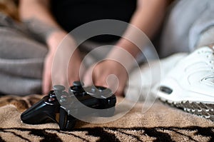Modern black game controller in the hands of a seated young girl