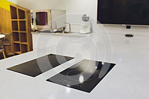 Modern black induction cooker on white countertop. kitchen with island.