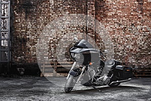 Modern black motorcycle stands against a brick wall