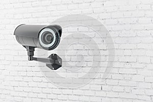 Modern black security camera installed on light brick wall