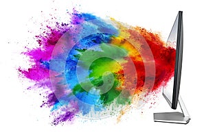 Modern black silver pc computer monitor with colorful rainbow spray holi powder cloud explosion through flat screen isolated white