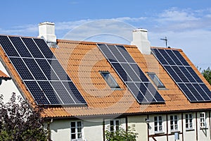 Modern black solar panels on the red tile roof of an old house