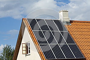 Modern black solar panels on the red tile roof of an old house