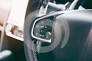 Modern black steering wheel with multifunction buttons for quick control, close-up in the car