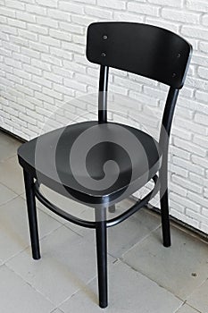 Modern black wooden chair in front of brick wall