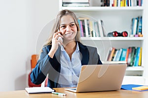 Modern blonde businesswoman speaking with customer at phone