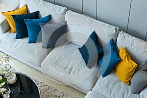 Modern blue yellow gray fabric pillows on gray cloth sofa interior in living room decoration design building