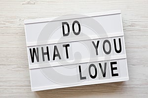 Modern board with text `Do what you love` word over white wooden background, top view. From above, flat lay