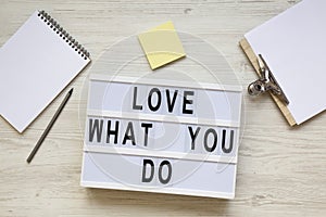 Modern board with text `Love what you do`, notepad, pencil and noticepad over white wooden background, top view. Business concep
