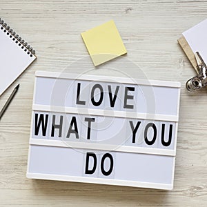 Modern board with text `Love what you do`, notepad, pencil and noticepad over white wooden background, top view. Business concep