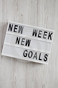 Modern board with text `New week new goals` over white wooden background, top view. From above, flat lay, overhead
