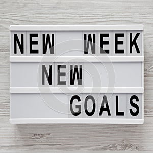 Modern board with text `New week new goals` over white wooden background, top view. From above, flat lay, overhead