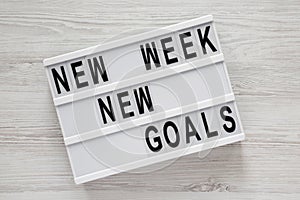 Modern board with text `New week new goals` over white wooden background, top view. From above, flat lay, overhead