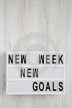 Modern board with text `New week new goals` over white wooden surface, top view. From above, flat lay, overhead. Copy space