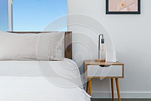 Modern bohemian desert home white bedroom with bed, side table, lamp