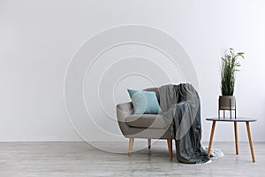 Modern boho cozy corner of home. Gray vintage armchair with blue pillow and blanket