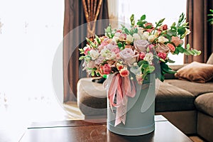 Modern bouquet of flowers in blue round box on a wooden table. Beautiful floral arrangement in a hat box. Flowers bouquet in