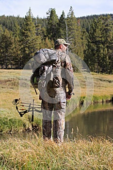 Modern bow hunter standing by a stream