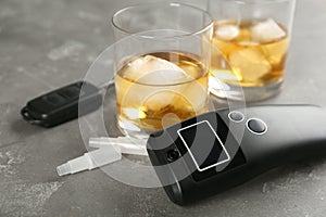 Modern breathalyzer and alcohol on grey stone table