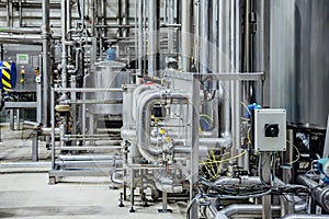 Modern brewery interior. Industrial stainless steel pipes connected with vats and control valves