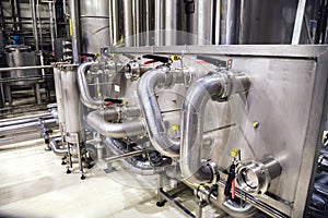 Modern brewery interior. Industrial stainless steel pipes connected with vats and control valves