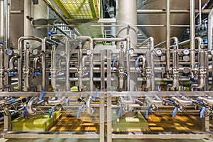 Modern brewery interior. Industrial stainless steel pipes connected with vats and control valves