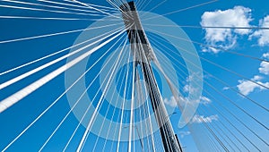 Modern bridge pylon against a blue sky. Detail of a multi-span cable-stayed bridge. White cable-stayed suspension bridge