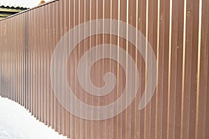 Modern brown metal corrugated siding fence, outdoor winter space, safety and security, veneer texture