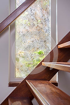 Modern brown staircase with wooden floor and glass barrier