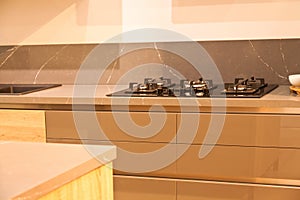 Modern brown wood oak kitchen cabinet equipment, white granite countertops and glass gas stove in a home