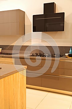 Modern brown wood oak kitchen cabinet equipment, white granite countertops and glass gas stove in a home