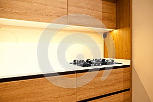 Modern brown wood oak kitchen cabinet equipment, white granite countertops and glass gas stove in a home