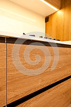 Modern brown wood oak kitchen detail cabinet equipment, white granite countertops and glass gas stove in a home