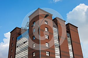 Modern building of brick and glass on a background of blue sky with clouds
