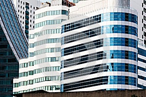 Modern building facade with glass windows sky color reflected and some lighted from the inside with white iron cladding building.