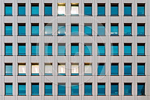 Modern building facade with window glass sky color reflected and some lighted from the inside