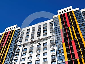 Modern building facade with windows, balconies and boxes for air conditioner on blue sky background