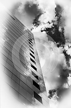Modern building reflecting clouds in turbulent sky B & W