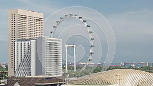 Modern buildings at downtown of Singapore timelapse and Giant Ferris wheel is visible on blue sky cityscape background