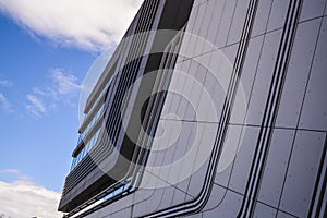 Modern buildings of unusual forms from glass and metal. Geometry of lines and curves. The inclined facade. Blue sky.