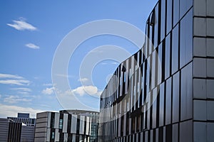 Modern buildings of unusual forms from glass and metal. Geometry of lines and curves. The inclined facade. Blue sky.